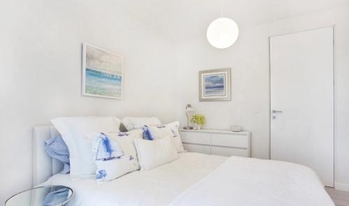 格丁尼亚Apartament Sea Towers View的白色卧室配有白色床和蓝色枕头