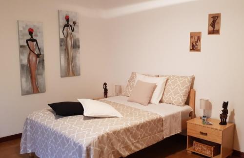 塔拉法尔B&B "Villa Alegria", Tarrafal的卧室配有一张床,墙上挂着两件连衣裙