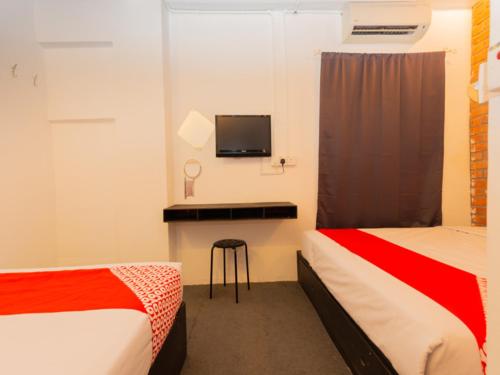 马六甲Super OYO 44032 Zzz Hotel的客房设有两张床和一张书桌及一台电视。
