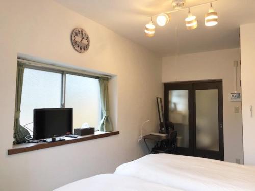 福冈Rapport Kukomae 207的卧室配有一张床,墙上挂着一个钟