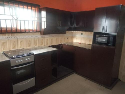 伊巴丹Tiffany Apartments的厨房配有黑色橱柜和炉灶烤箱。