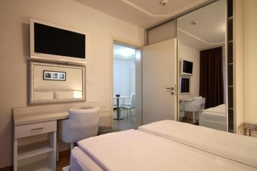 布德瓦阿鲁巴酒店的酒店客房带一张床、一张书桌和一面镜子