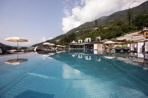 圣马蒂诺Quellenhof Luxury Resort Passeier的一座大游泳池,后面是群山