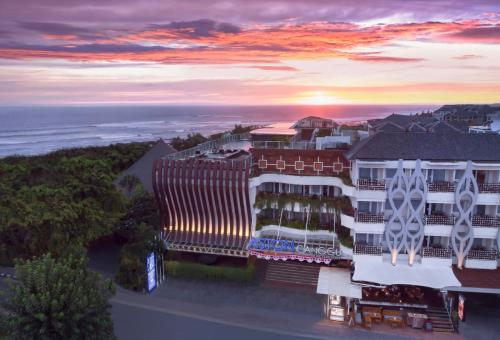 坎古ASTON Canggu Beach Resort的建筑的空中景观,背景是日落