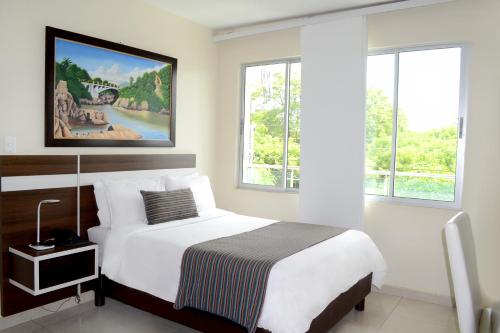 巴耶杜帕尔Hotel Metropolitano Plaza的卧室配有一张床,墙上挂有绘画作品