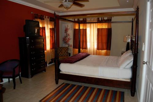 Bon Accord Village卡萨戴尔苏多巴哥别墅的一间卧室配有一张床、一台电视和一个梳妆台