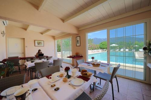菲加里特拉科斯度假屋的一间带白色桌椅的餐厅和一个游泳池