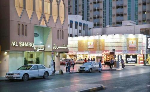 沙迦Al Sharq Hotel - BAITHANS的一条城市街道,汽车停在建筑前