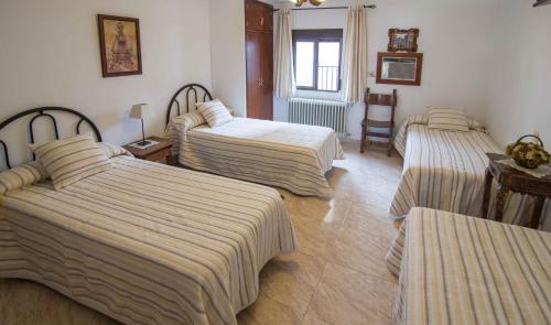 瓜达卢佩阿尔巴塔鲁塔旅馆的酒店客房,配有3张带条纹床单的床