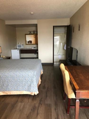 雷德迪尔Red Deer Inn & Suites的一间卧室配有一张床铺和一张桌子,还设有一间厨房