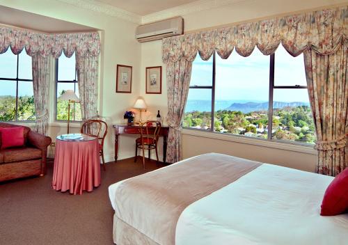 肯图巴Mountain Heritage Hotel的卧室配有一张床、一张书桌和窗户。
