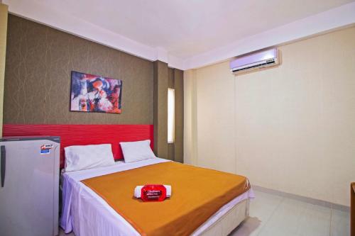 雅加达RedDoorz near Cilandak Town Square的一间卧室配有一张带红色床头板的床和一台冰箱