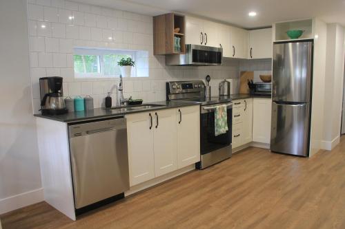 温哥华HiddenGem-private modern suite on trendy Main St的厨房配有白色橱柜和不锈钢冰箱