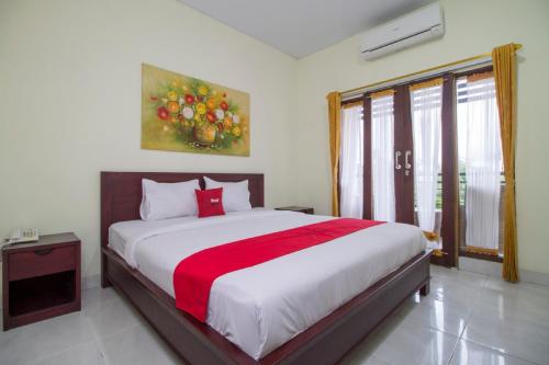 库塔RedDoorz at Benesari 2 Legian的一间卧室配有一张带红色毯子的大床