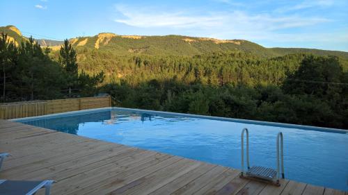EntrepierresGîtes L Aousière的一座带甲板的游泳池,其背景是山脉