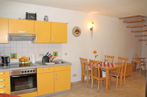 卡尔斯哈根Ferienwohnungen Karlshagen USE 3010的厨房配有黄色橱柜和桌椅