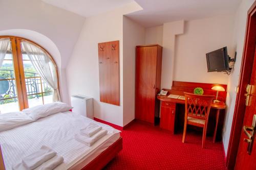 Koziegłowy斯塔利梅林酒店的一间卧室配有一张床、一张书桌和一个窗户。