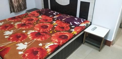帕坦科特Sai Guest House的一张带花卉棉被和桌子的床