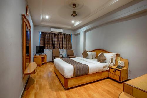 拉杰果德JMC集团酒店的一间卧室配有一张床、一张书桌和一个窗户。