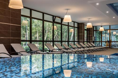 帕兰加Gradiali Wellness and SPA的客房设有带椅子和窗户的游泳池。