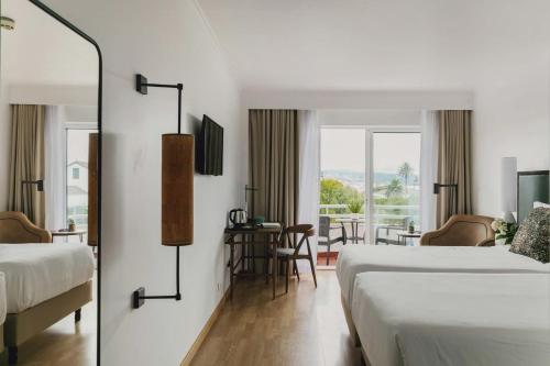 蓬塔德尔加达蓬塔德尔加达酒店的酒店客房带两张床和一张桌子以及椅子。