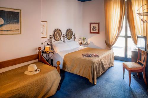 阿斯蒂帕利欧酒店的一间卧室设有两张床,椅子上有一顶帽子