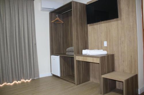 阿帕雷西达Ouro Minas Plaza Hotel的一间配有电视的房间和一张长凳