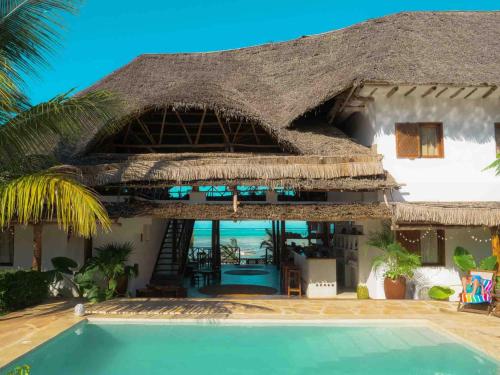 平圭Hekaya Zanzibar的一个带游泳池和茅草屋顶的度假胜地