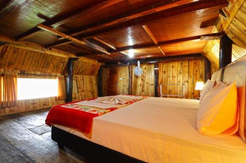 图克图克笃笃提姆布尔简易别墅的木墙客房内的一张大床