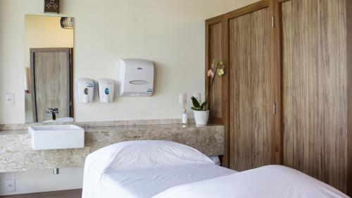 马塞约Jatiuca Hotel & Resort的一间卧室配有床、水槽和镜子