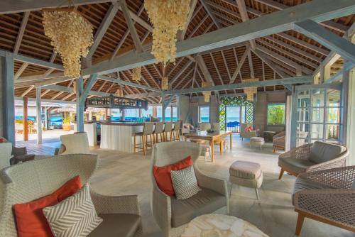 Johnsons PointCocobay Resort Antigua - All Inclusive - Adults Only的大堂设有桌椅和酒吧。