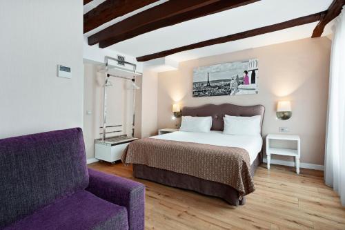 巴黎Exe Paris Centre的一间卧室配有一张床和一张紫色沙发