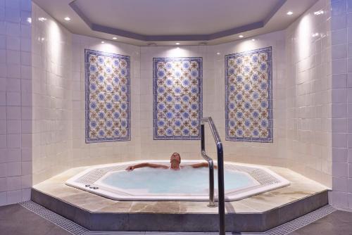 丰沙尔波尔图湾度假酒店的男人在浴缸里,在浴室里,窗户