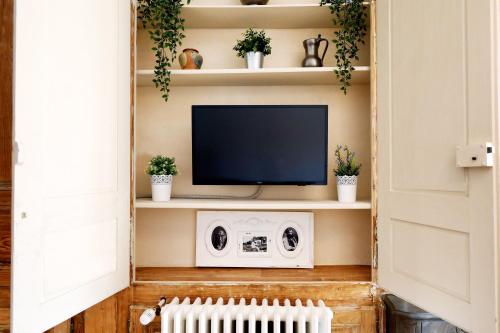 萨兰莱班L'Aristoloche的客厅配有电视和植物架
