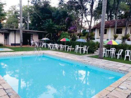 伊比乌纳Hotel Fazenda Bandeirantes的庭院内带椅子和遮阳伞的游泳池