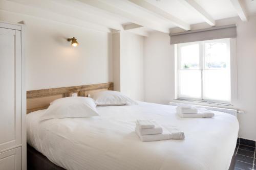 伊普尔Cottage de Vinck的卧室配有白色的床和2条毛巾