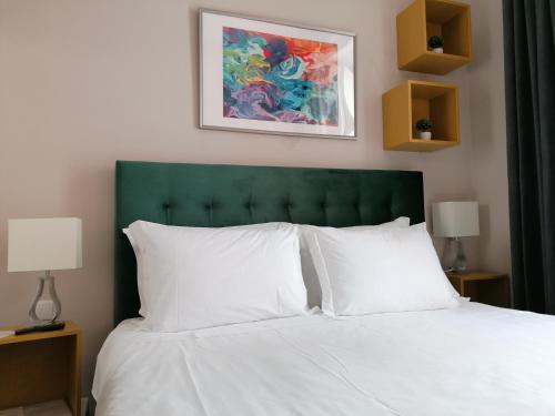 波尔蒂芒Temple Suites Guesthouse的一张带绿色床头板和白色枕头的床