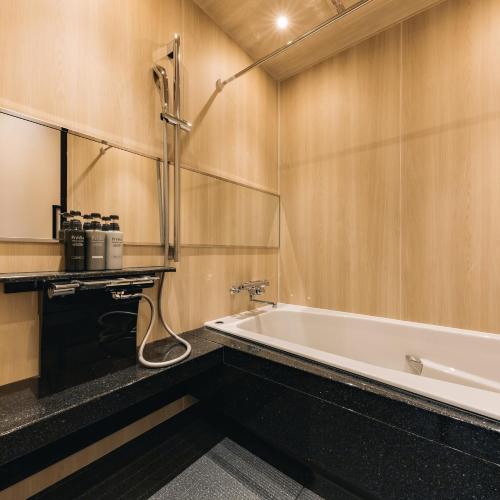 大阪Hotel Yururito Osaka的带浴缸和镜子的浴室