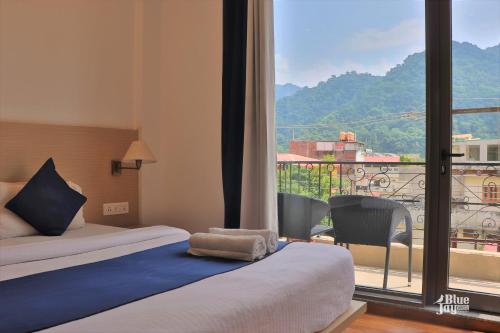 瑞诗凯诗Blue Jay Hostel Rishikesh的酒店客房设有一张床和一个大窗户