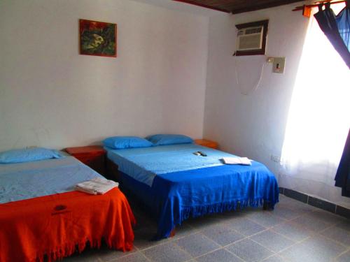 莱蒂西亚Hotel Huito的配有两张蓝色和红色床单的床铺