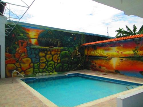 莱蒂西亚Hotel Huito的一座建筑的一侧,设有一座带壁画的游泳池