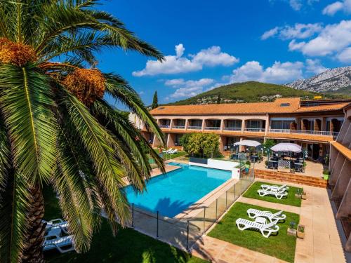 拉瓦雷特迪瓦尔Noemys Toulon La Valette - Hotel restaurant avec piscine的一个带游泳池和棕榈树的度假村