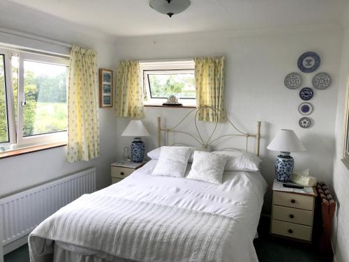 锡廷伯恩Holly House B&B的卧室配有白色的床和2扇窗户。
