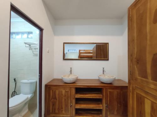 珀尼达岛Gedhong Hostel的浴室设有2个水槽、卫生间和镜子。