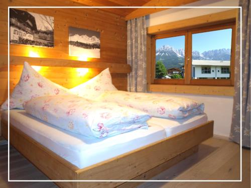 埃尔毛Alpen Chalet ELLMAU Zentrum的卧室配有带枕头的床铺和窗户。