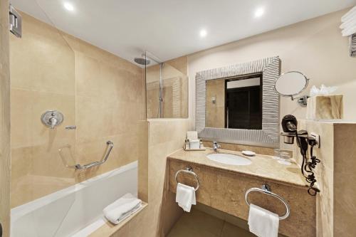 棕榈滩巴塞罗阿鲁巴全包度假酒店的一间带水槽、浴缸和镜子的浴室