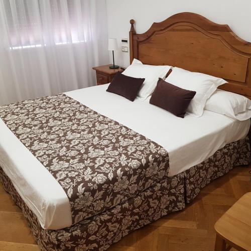 佩德罗－穆尼奥斯Hostal La Parada的卧室配有一张带白色床单和枕头的大床。