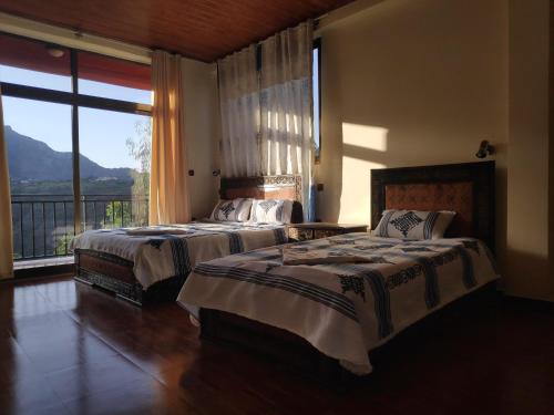 拉利贝拉Merkeza Guest House的卧室设有两张床和大窗户