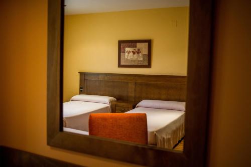 DeifontesHostal Rural el Nacimiento的镜子反射着带两张床和椅子的房间