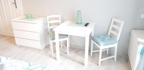 弗罗茨瓦夫Colourful Rooms Wrocław的一张带两把椅子的白色桌子和花瓶